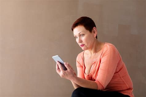 Femme Mature Avec Un Smartphone Surpris Photo Gratuite