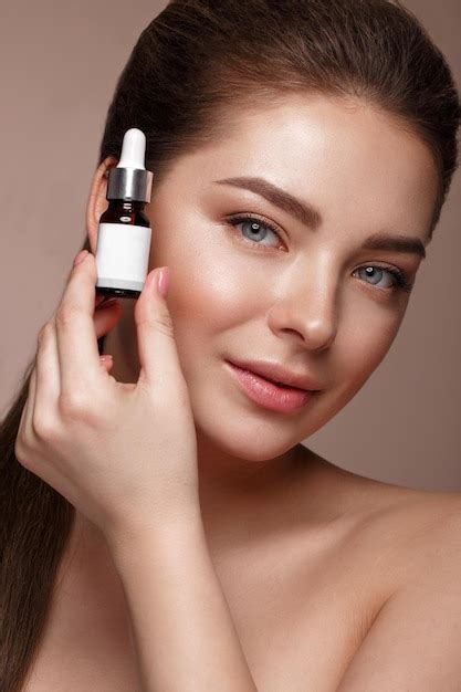 Belle jeune femme avec un maquillage nude naturel avec un cosmétique dans les mains Photo Premium