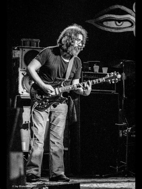 A Man Standing On Top Of A Stage Holding A Guitar