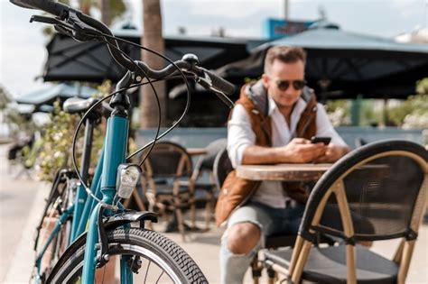 Homem verificando o telefone ao lado de uma bicicleta Foto Grátis