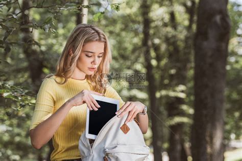 金发女金发女子在公园把数字平板电脑和空白屏高清图片下载 正版图片503403526 摄图网