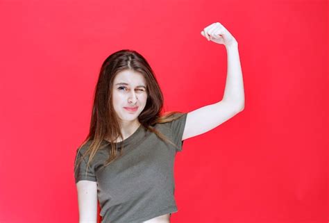 Fille En Chemise Verte Démontrant Ses Muscles Du Bras Photo Gratuite