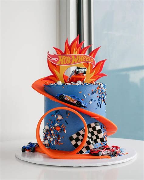 A Birthday Cake With Cars And Flames On The Top Is Sitting On A White Table