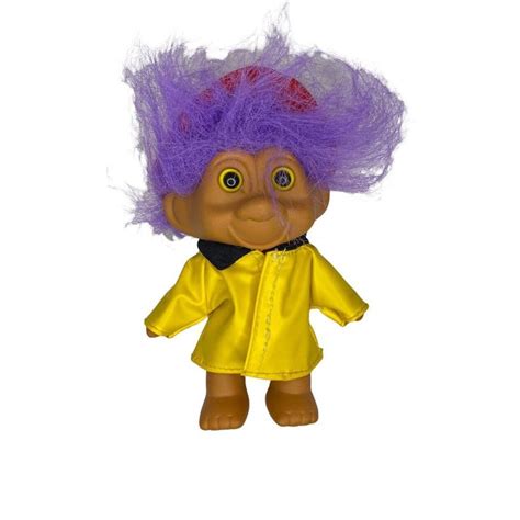 A Troll Doll With Purple Hair Wearing A Yellow Jacket