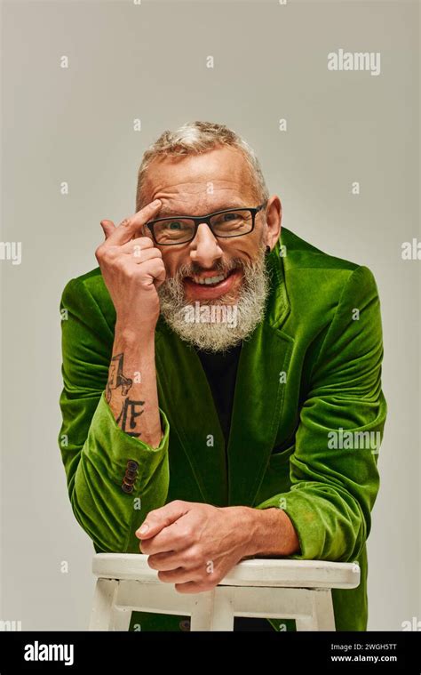 Good Looking Joyous Mature Man In Vivid Attire Posing With Tall Chair