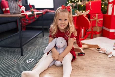 Adorable Blonde Girl Smiling Confident Sitting On Floor By Christmas