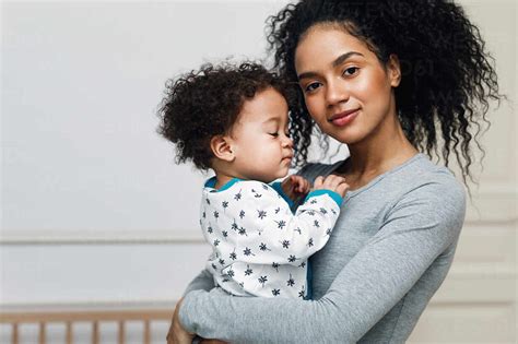 Portrait Of Confident Smiling Mother Carrying Baby Boy At Home Stock Photo