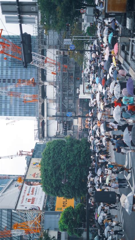 a crowd of people standing on the side of a road next to tall buildings under construction