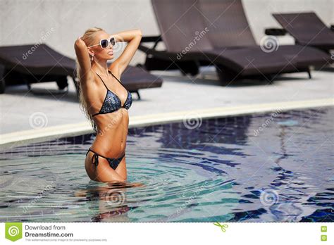 De Elegante Vrouw In Bikini Met Het Gelooide Slanke Lichaam Stellen Dichtbij Zwemt Stock Foto