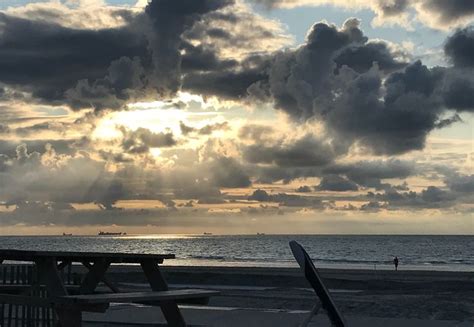 The Sun Is Shining Through Some Clouds Over The Ocean And Beach Chairs