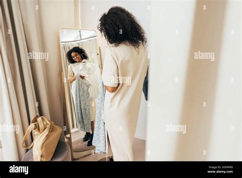 Young Stylish Woman In Fitting Room Looking At Mirror Trying On New