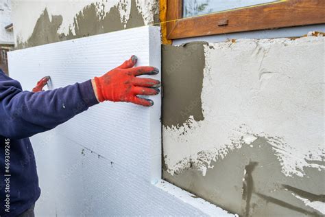 Construction worker installing styrofoam insulation sheets on house ...