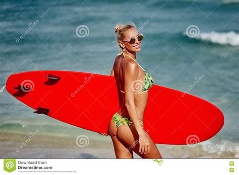 Belle Fille De Surfer De Jeune Femme Dans Le Bikini Avec La Planche De Surf Sur Le Th Image