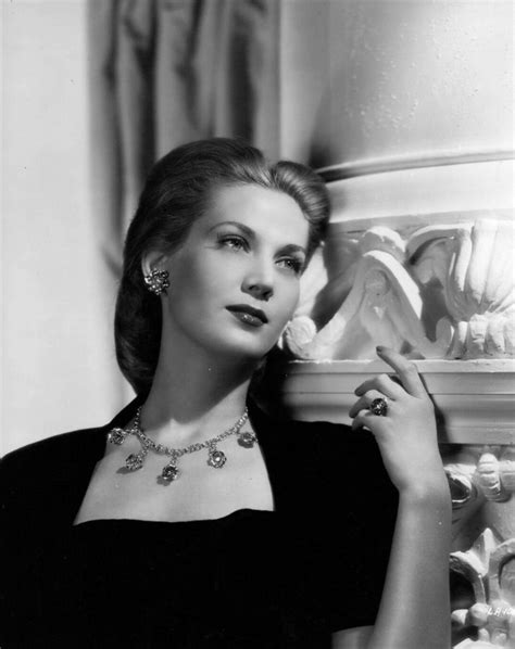 An Old Black And White Photo Of A Woman Leaning Against A Wall Wearing