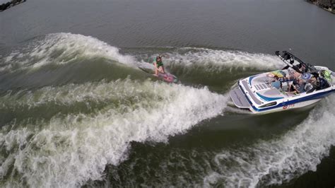 Aerial shot of a man wakeboard wake surfing behind a boat on a lake ...