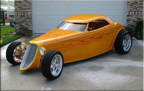 An Orange Car With Flames Painted On It S Side Parked In Front Of A Garage