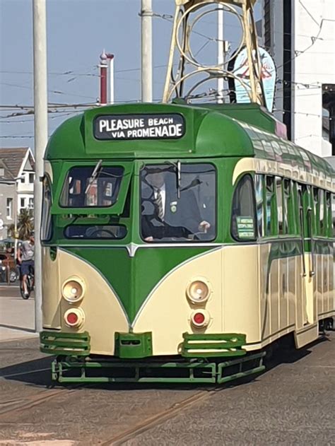 A Green And White Trolley Car Traveling Down The Street