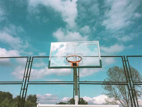 Green And Orange Basketball Hoop Near Green Chain Link Fence Under