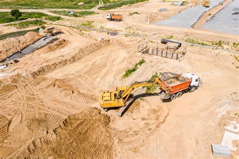 Backhoe Loading Ground Into A Dump Truck On Construction Site Birds