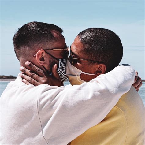 Premium Photo Gay Couple Wearing Masks Kissing Against Sky