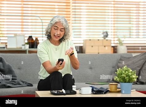 Diabetic Mature Woman Measuring Blood Glucose With Glucose Meter At