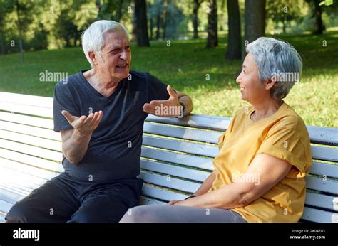 Older Couple Multi Racial Spouses Sit Rest On Bench Enjoy Talk In Public Summer Park Having