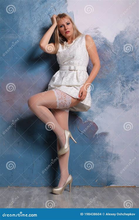 Long Legged Blonde Girl In White Stockings Posing At The Wall Stock Photo Image Of Legged