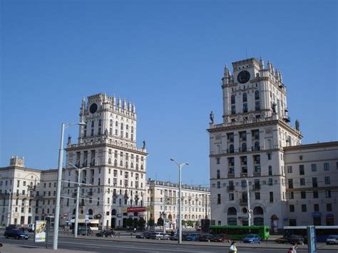 Two Large White Buildings With Clocks On The Top Of Them And Cars