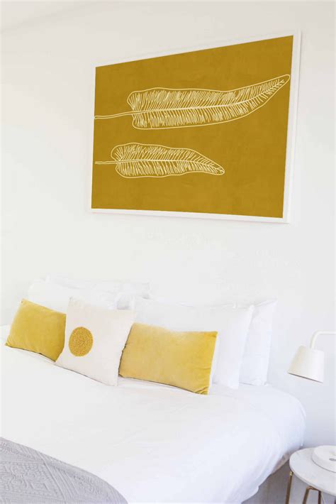 photo of the bedroom with mustard yellow pillows and large artwork ...