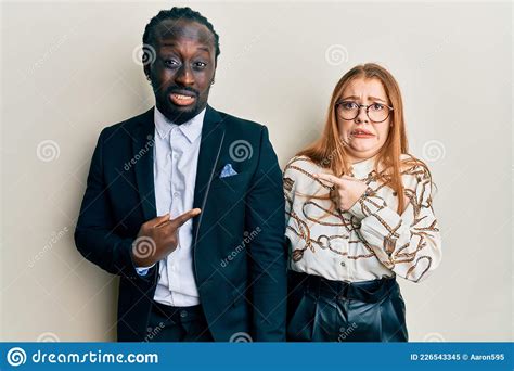 Young Interracial Couple Wearing Business And Elegant Clothes Pointing