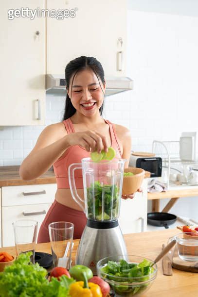 A Fit And Healthy Asian Woman In Sportswear Is Making A Green Smoothie