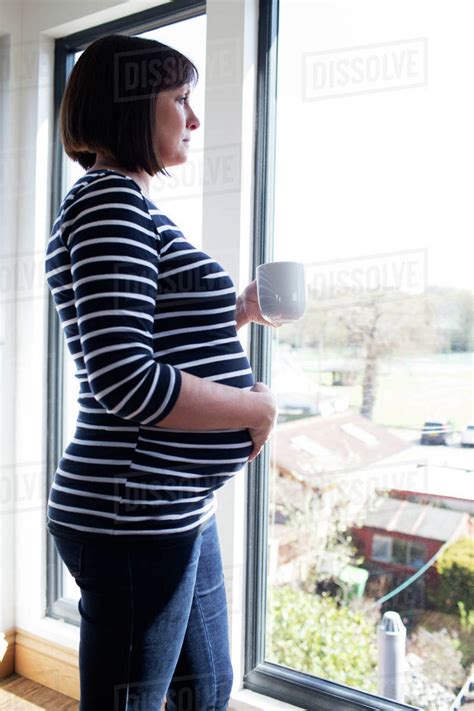 Mature Pregnant Woman Looking Out Of Window At Home Royalty Free Stock Photo Dissolve