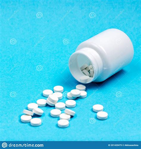 White Pharmaceutical Pills And White Inverted Jar On A Light Blue