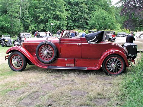 An Old Red Car Is Parked In The Grass