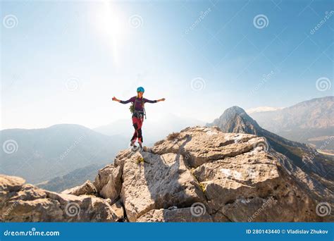 Young Girl Climber In A Helmet And With A Backpack Stands On Top Of A