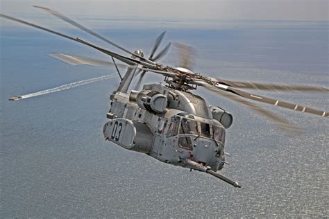 A CH-53K King Stallion helicopter prepares to plug into a funnel-shaped ...