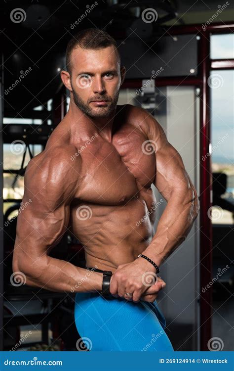 Vertical Shot Of A Young Attractive Fit Male Posing While Flexing His Muscles In The Gym Stock