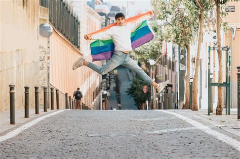 Jovem Segurando Uma Bandeira Do Orgulho Gay Pulando Na Rua Conceitos De Estilo E Liberdade