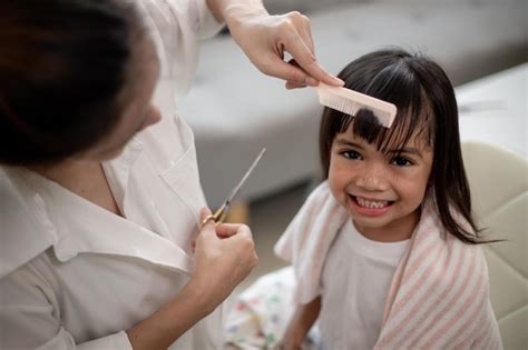 Premium Photo Asian Mother Cutting Hair To Her Daughter In Living