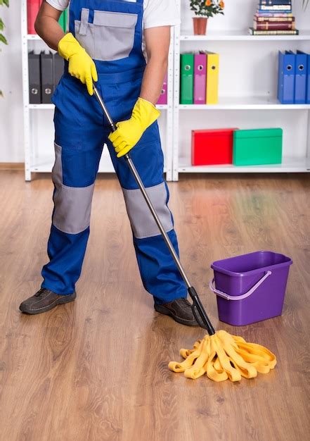 Premium Photo Young Man In Blue Uniform Is Cleaning The Floor