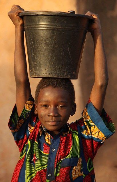 Boy carrying a bucket of water | Water bucket, African children, Africa people