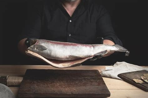 Premium Photo Midsection Of Man Holding Fish On Cutting Board