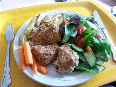 A White Plate Topped With Meat And Veggies On Top Of A Yellow Tray