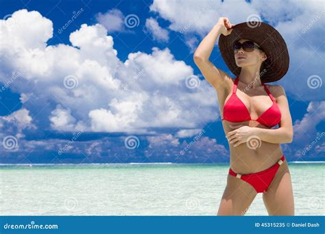 Cappello D Uso Della Donna E Bikini Rosso Sulla Spiaggia Tropicale