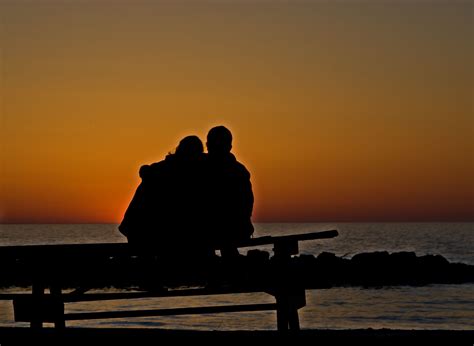 Couple Sitting On Picnic Table Watching The Sunset Presque Isle Beach