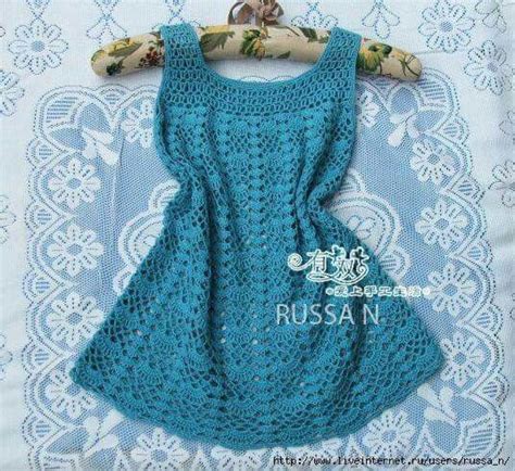 A Blue Crocheted Dress Is Hanging On A Lace Doily