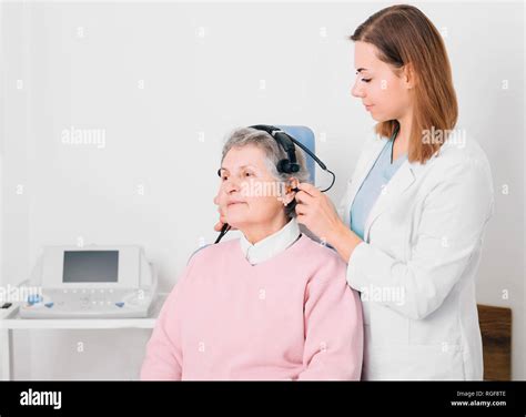 Audiologist Doing Hearing Exam With Special Headphones To Older Woman