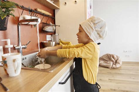 Lächelnder Junge beim Händewaschen in der Küche zu Hause lizenzfreies