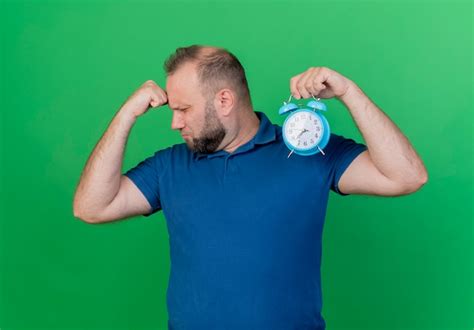 Free Photo Tired Adult Slavic Man Holding Alarm Clock Turning Head