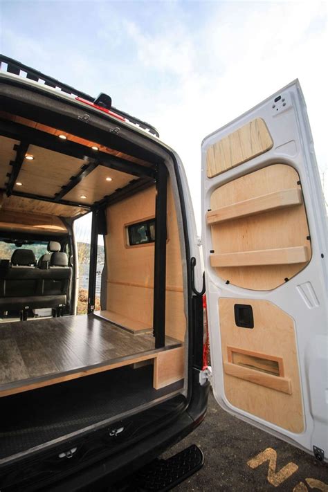 The Back End Of A White Van With Its Doors Open And Wood Shelves In Place